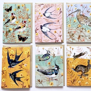May include: Set of six greeting cards featuring colorful illustrations of birds, butterflies, and other wildlife against a backdrop of green and yellow foliage.
