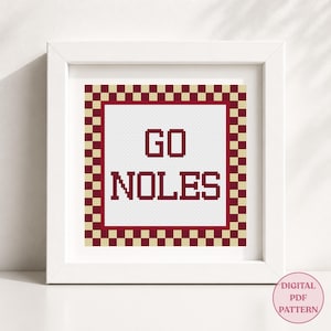 Può includere: Un motivo a punto croce quadrato in una cornice bianca con il testo GO NOLES in lettere maiuscole rosso scuro. Il design è circondato da un bordo a scacchi con quadrati alternati rosso scuro e crema su uno sfondo in tessuto bianco.
