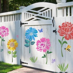 May include: A white wooden fence and gate featuring colorful floral decals including a pink flower, a yellow sunflower, a blue daisy, and a large red peony. The design also includes small butterflies, a bee, and green grass accents.