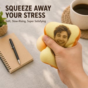 May include: A soft, squishy, bread-shaped stress relief toy featuring a custom printed portrait of a smiling person on the surface. The text SQUEEZE AWAY YOUR STRESS and Soft, Slow-Rising, Super Satisfying is printed in the background.