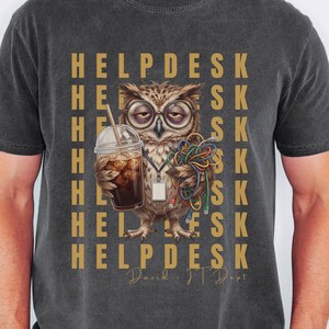 May include: A charcoal gray t-shirt featuring a graphic of an owl wearing glasses, holding an iced coffee and a bundle of colorful computer cables. The background text repeats the word HELPDESK in gold, with David - IT Dept written below.