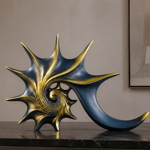Könnte beinhalten: Eine dekorative Skulptur in Form einer spiralförmigen Muschel mit scharfen, spitzen Kanten. Das Objekt hat eine tief dunkelblaue Oberfläche, die durch ein metallisches Gold-Finish an der inneren Spirale und den Spitzen akzentuiert wird.