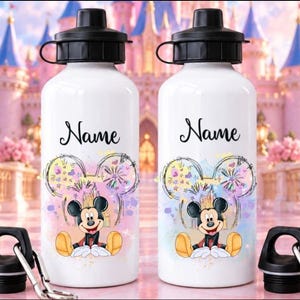 May include: Two white metal water bottles with black screw-top lids and carabiners. Each bottle features a colourful graphic of Mickey Mouse sitting in front of fireworks, with the word Name printed in black script above the character design.