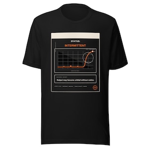 May include: A black short-sleeve t-shirt featuring a graphic print of a technical status screen. The design includes the text STATUS: INTERMITTENT, a line graph with an orange curve, and the warning text Output may become orbital without notice.
