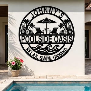 May include: A circular black metal wall sign featuring the text JOHNNY'S POOLSIDE OASIS and RELAX, SWIM, UNWIND. The design includes silhouettes of two lounge chairs, a table with drinks, an umbrella, palm trees, and ocean waves.
