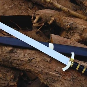 Pode incluir: Uma espada de lâmina reta com uma lâmina prateada polida, uma guarda dourada e um cabo preto com faixas douradas. A espada é acompanhada por uma bainha preta com detalhes metálicos dourados na ponta e na boca da bainha.