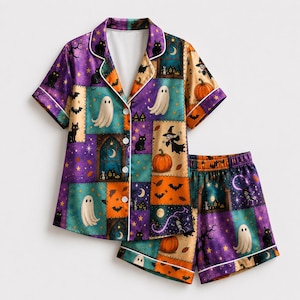May include: A short-sleeve button-down pajama shirt and matching shorts set featuring a colorful patchwork print of Halloween motifs including ghosts, black cats, pumpkins, bats, witches, and haunted houses in shades of purple, orange, and teal.