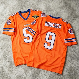 May include: Two orange athletic jerseys with blue and white trim. The front features the number 9, the text THE WATERBOY, and a circular logo. The back displays the name BOUCHER above the number 9. Both sleeves have blue and white stripes.