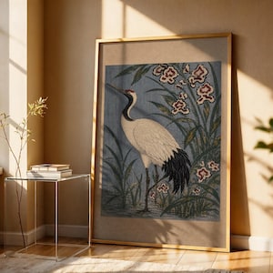 May include: A framed vertical wall art print featuring a white crane with a black neck and tail standing in a blue-toned marsh with green reeds and white flowers with red centers. The artwork is enclosed in a thin, light-colored wooden frame.
