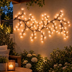 May include: A wall-mounted decorative light fixture featuring dark, branching stems adorned with numerous small, glowing flower-shaped bulbs that emit a warm, soft light across the surface, creating an illuminated floral pattern.