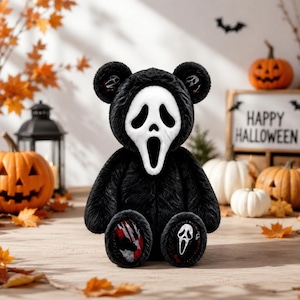 Pode incluir: Um urso de peluche com pelo preto, apresentando uma máscara branca de Ghostface a cobrir o rosto. O urso tem padrões de salpicos de sangue vermelhos e pretos nas solas dos pés, com um pequeno ícone de máscara Ghostface no pé direito.
