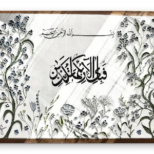 Può includere: Un'opera d'arte murale rettangolare in una cornice di legno scuro con calligrafia araba nera centrata su uno sfondo bianco. Il design è bordato da viti floreali in rilievo in tonalità blu, verde e bianco, con ulteriore scrittura nella parte superiore.