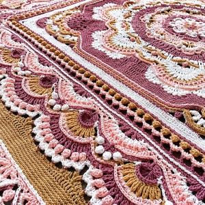 Könnte beinhalten: Eine Häkeldecke mit einem komplexen Mandalamuster in den Farben Altrosa, Senfgelb, Weiß und zartem Rosa. Das Design umfasst aufwendige Maschenarbeiten, darunter erhabene Noppen, Muschelmotive und strukturierte Ränder.