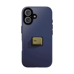 Puede incluir: Una funda de smartphone azul oscuro con un recorte para cámara de doble lente en la parte superior izquierda y una tecla de teclado de computadora de color verde oliva, elevada y centrada en la parte posterior. La tecla cuadrada muestra el texto Esc.