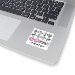 Könnte beinhalten: Ein quadratischer Aufkleber mit einem Pixel-Art-Design aus einem grauen Steuerkreuz-Gitter, zwei rosa runden Knöpfen mit der Beschriftung B und A, einem grauen rechteckigen Knopf mit der Aufschrift START und dem Wort cheater in schwarzer Pixelschrift.