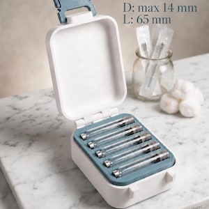 Puede incluir: Un estuche de almacenamiento rectangular blanco con un cierre y un inserto interior azules, que contiene cinco cartuchos de vidrio transparente. El estuche incluye el texto FITS CARTRIDGES D: max 14 mm L: 65 mm para organizar objetos cilíndricos.