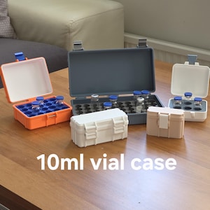 May include: A collection of 10ml vial cases in various colors including orange, grey, white, and beige. The cases feature hinged lids with secure latches and internal foam inserts with circular cutouts designed to hold multiple glass vials securely.