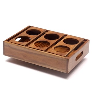 May include: A rectangular brown wooden serving tray featuring six circular cutouts arranged in two rows of three. The tray has a smooth finish with visible wood grain and includes integrated handles on the shorter side panels for easy carrying.