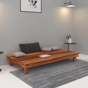 May include: A low-profile rectangular wooden platform bed frame featuring a rich brown wood grain finish, supported by four sturdy cylindrical legs. The frame is topped with one large dark gray rectangular pillow and two smaller light gray pillows.