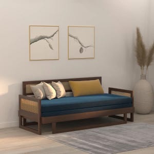 May include: A daybed with a dark brown wooden frame and natural cane side panels. It features a long, deep blue seat cushion, two light beige square throw pillows, and one rectangular mustard yellow throw pillow placed on the blue cushion.