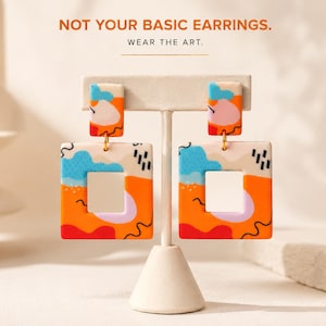 Peut inclure: Boucles d'oreilles carrées avec un motif abstrait coloré composé de lignes orange, bleues, roses et noires sur fond crème. Le texte NOT YOUR BASIC EARRINGS. WEAR THE ART. est affiché au-dessus des boucles suspendues à un support en T.