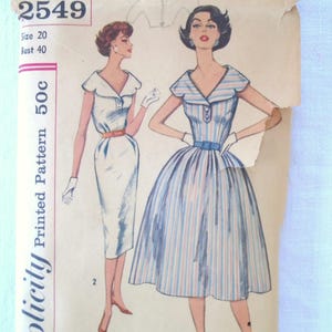May include: A vintage Simplicity sewing pattern envelope, number 2549, size 20, bust 40. The illustration features two dress styles: a solid white sheath dress and a striped dress with a full skirt, both with V-necklines and belts.