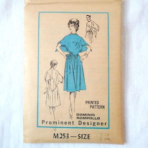 May include: Vintage sewing pattern for a dress with a cape-like top. The pattern is printed on paper and features a woman wearing the dress. The pattern is for size 12 and is by Dominic Rompollo, a prominent designer.