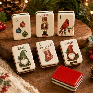 Könnte beinhalten: Ein Set aus sechs rechteckigen Mahjong-Spielsteinen mit cremefarbenen Vorderseiten und rot-grün gestreiften Kanten. Die Spielsteine zeigen festliche Illustrationen wie Weihnachtskugeln, einen Nussknacker, einen Kardinal, Wichtel und einen Strumpf mit Text.