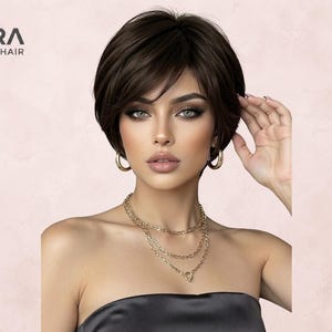 May include: A short, dark brown human hair wig with side-swept bangs and layered volume. The text LORA HUMAN HAIR is visible in the upper left corner. The wig features a natural-looking texture and a sleek, polished finish, framing the face.