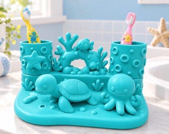 May include: A teal toothbrush holder featuring a sea-themed design with a turtle, an octopus, coral, and starfish accents. The holder has two cylindrical compartments for toothbrushes, one containing a yellow brush and the other a pink brush.