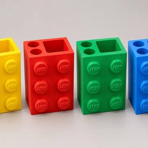 Può includere: Quattro organizer da scrivania rettangolari a forma di grandi mattoncini da costruzione in giallo, rosso, verde e blu. Ogni organizer presenta sei perni circolari sulla parte anteriore, ciascuno con il logo LEGO in rilievo, e due aperture tonde e una quadrata.
