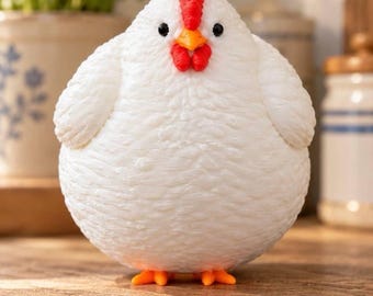 May include: A round, white chicken figurine with a textured, feather-like surface. It features a bright red comb and wattle, a small yellow beak, and two small black eyes. The chicken stands on two small, orange, three-toed feet.
