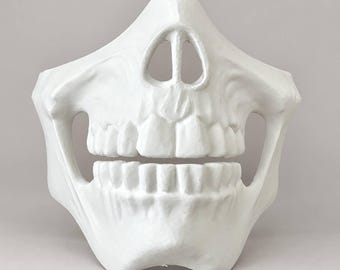 May include: A white, molded half-face mask featuring a detailed human skull design. The mask covers the nose, cheekbones, and jaw area, showcasing a prominent nasal cavity, defined upper and lower teeth, and open side sections.