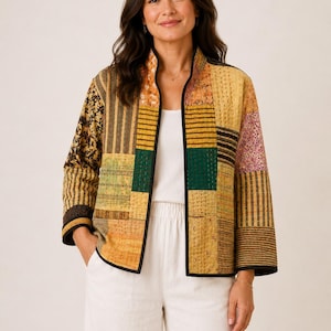 Peut inclure: Une veste matelassée à manches longues avec un motif patchwork composé de divers imprimés dans des tons jaune moutarde, vert foncé, noir et floral. La veste présente un col montant, une ouverture frontale et un liseré noir sur les bords.