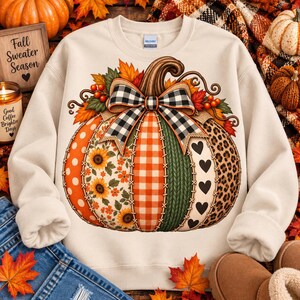 Peut inclure: Un sweat-shirt à col rond couleur crème arborant un grand motif central de citrouille en patchwork. Le design de la citrouille comprend des sections à pois orange, des tournesols, du vichy orange, une texture tricotée verte, des cœurs noirs.