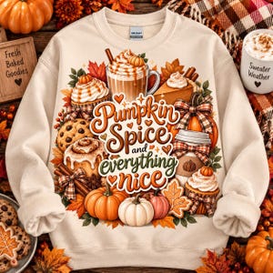 May include: A cream-colored crewneck sweatshirt featuring a colorful graphic print of autumn-themed treats, including a pumpkin spice latte, cinnamon rolls, cookies, and pumpkins, with the text Pumpkin Spice and everything nice in orange script.