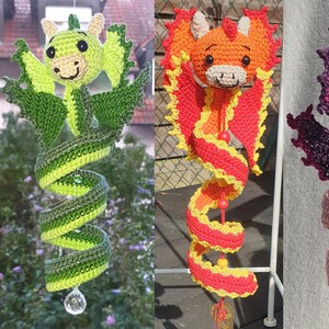 Könnte beinhalten: Vier hängende Häkel-Drachen-Ornamente in den Farbschemata Grün, Orange und Gelb, Violett und Rosa sowie Blau. Jeder Drache hat einen geringelten Schwanz, Flügel und eine kleine Kristallperle am unteren Ende, aufgehängt an einer Schnur mit Perlen.