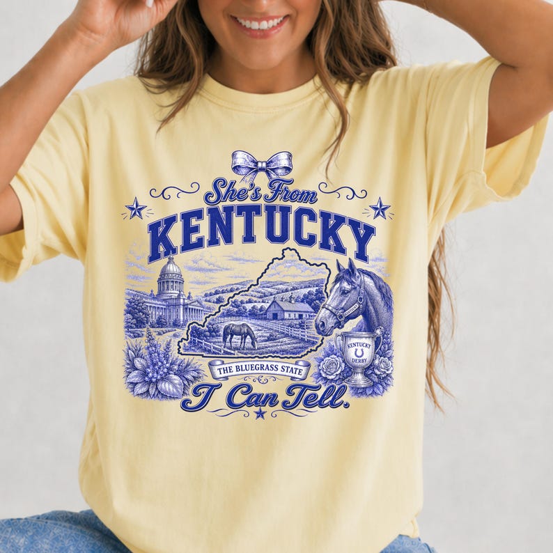 A woman wearing a yellow t-shirt with a graphic design featuring a horse, flowers, and text related to Kentucky.