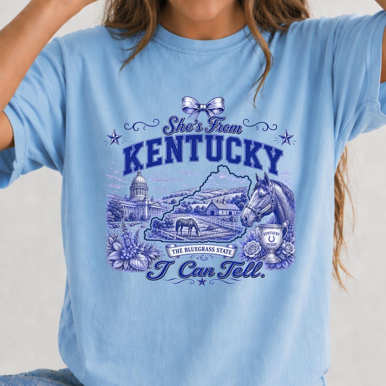 A blue t-shirt with a graphic design featuring a horse, a state map, and various decorative elements.