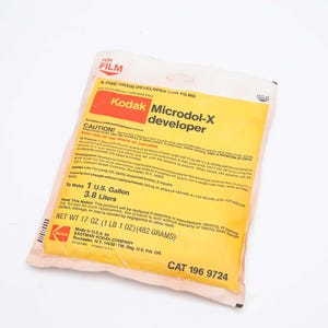 May include: A package of Kodak Microdol-X developer for films. The yellow and red package has the text "Kodak Microdol-X developer" and "NET WT 17 OZ (1 LB 1 OZ) (482 GRAMS)". The package is sealed and has the text "CAT 196 9724".