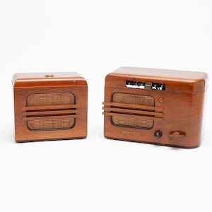 May include: Two vintage wooden radios. The radios are brown with a rectangular shape and a speaker grill. The larger radio has knobs and dials on the top. The smaller radio has a simple design. Both radios have the word "PHILCO" on the bottom.