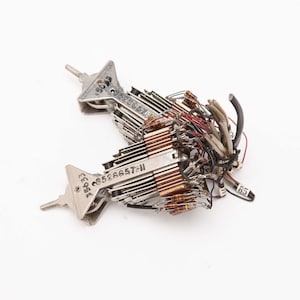 May include: Two silver-colored electronic components with attached wires and resistors. Each component has a triangular shape with a screw and stamped text, including "8526657-11". A bundle of wires and a label marked "85" are also visible.