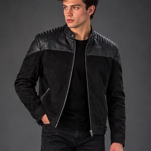 Peut inclure: Une veste noire dotée d'un empiècement supérieur en cuir lisse avec des détails matelassés aux épaules, un corps en suédine, un col montant et une fermeture éclair frontale, portée avec un t-shirt noir, un jean noir et des bottes en cuir noir.