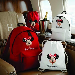 May include: Two backpacks and two drawstring bags in red and white. Each bag features a graphic of a Minnie Mouse balloon with a red and white polka dot bow and the text Your Name printed below the character graphic on the front of each item.