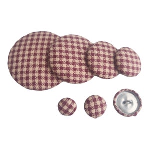 May include: Set of six brown and beige gingham fabric buttons. The buttons are in various sizes, with the largest button measuring approximately 2 inches in diameter.