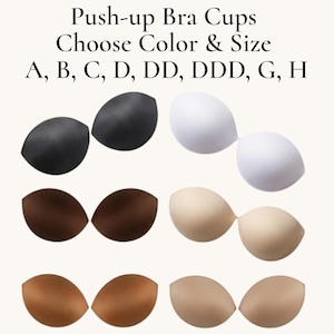 May include: A selection of push-up bra cups in various colors, including black, white, and shades of brown and beige. The image includes text that reads "Push-up Bra Cups Choose Color & Size A, B, C, D, DD, DDD, G, H."