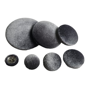 May include: Assortment of six grey velvet buttons in various sizes. The buttons are round and have a smooth, soft texture.