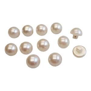 May include: A collection of 12 white pearl-like buttons, including two shank buttons. The buttons are round and have a smooth, glossy finish.