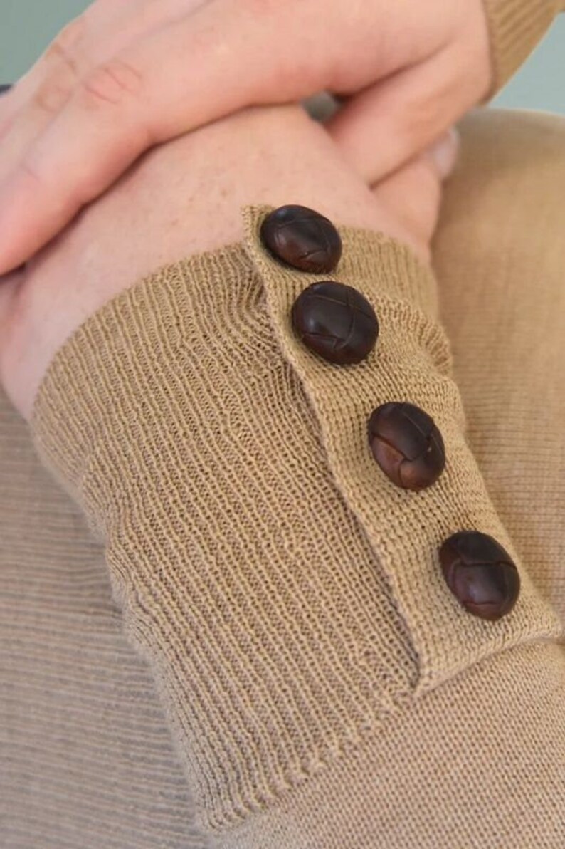 May include: A brown knitted sweater with four brown leather buttons on the cuff.