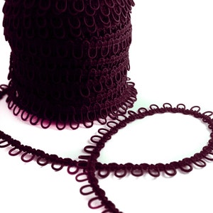 May include: A roll of dark purple elastic trim with small loops. The trim is laid out in a circle and a heart shape.